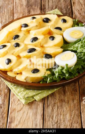 Papa a la Huancaina plat de pommes de terre en tranches avec une sauce spéciale gros plan dans l'assiette sur la table.Verticale Banque D'Images