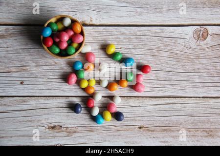 Bonbons à base d'arachides avec glaçage au sucre coloré, dans un bol en bois sur une ancienne table en bois. Banque D'Images