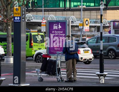 Les passagers doivent passer un panneau d'information au terminal 3 de l'aéroport d'Heathrow, Londres, pour signaler les nouveaux frais de dépôt pour les personnes transportant des voyageurs vers l'aéroport en véhicule.Date de la photo: Lundi 8 novembre 2021. Banque D'Images