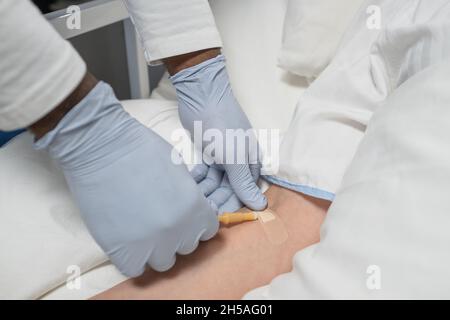 Gros plan du médecin en gants de protection mettant l'anesthésie n le bras d'un patient avant l'opération Banque D'Images