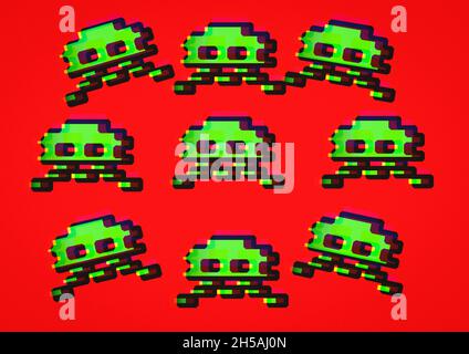 Vintage 80's Retro Pixel art, un ensemble de envahisseurs étrangers verts de l'espace dans un style graphique 8-bit 2D pixelated sur un arrière-plan rouge vif Banque D'Images