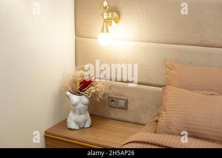 Vase en pierre moderne silhouette féminine avec fleurs séchées sur la table de chevet dans la chambre.Mise au point sélective et douce, bruit artistique Banque D'Images