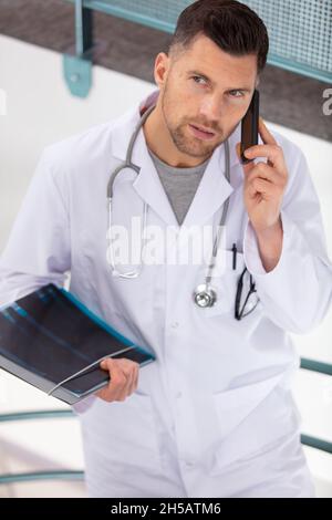 un médecin grimace se promenant dans les escaliers parlant au téléphone Banque D'Images