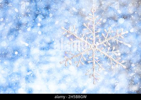 Flocon de neige dans la neige.Flocon de neige blanc sur un arrière-plan blanc-bleu brillant et flou.Copier l'espace.Modèle pour la conception Banque D'Images