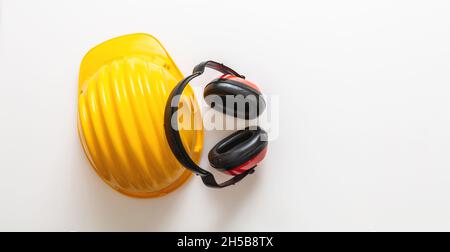 Casque de sécurité et protections auditives.Protection de la tête et de l'ouïe isolée sur fond blanc, bannière.Casque de protection individuelle, jaune dur ha Banque D'Images