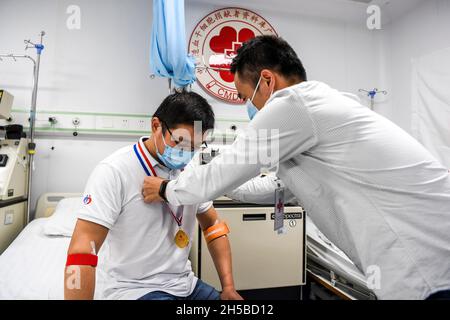 (211108) -- NANNING, 8 novembre 2021 (Xinhua) -- Un membre du personnel remet une médaille au docteur Li à l'hôpital affilié de la première université médicale de Guangxi à Nanning, dans la région autonome de Guangxi Zhuang, dans le sud de la Chine, en novembre 2021.Li, un médecin du département d'hématologie du premier hôpital affilié de l'Université médicale de Guangxi, s'est inscrit auprès du Programme des donneurs de moelle de Chine (PDMC) en tant que donneurs potentiels de cellules souches hématopoïétiques (HSC) en novembre 2011.En tant que médecin traitant des cellules souches hématopoïétiques pour les patients, il a réussi à faire correspondre un patient en tant que donneur HSC en août 20 Banque D'Images