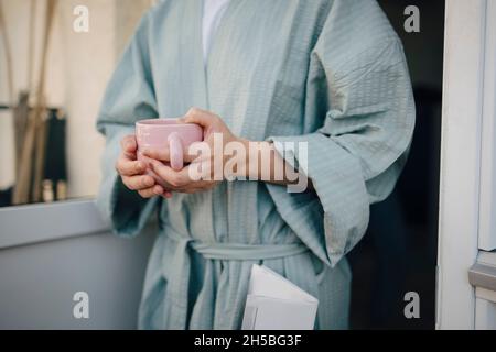 Section médiane de la femme tenant une tasse à café Banque D'Images