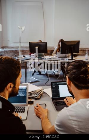 Les programmeurs masculins font le codage sur ordinateur portable à la société de démarrage Banque D'Images