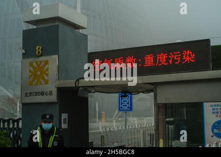 Caractères chinois sur l'écran LCD: Qualité de l'air: Pollution lourde.Un homme garde une tour enveloppée par un épais smog à Beijing, en Chine.06 novembre 2021 Banque D'Images