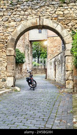 Bicycle se trouve dans la porte voûtée en pierre naturelle, qui se connecte à un mur médiéval de la ville en Allemagne Banque D'Images