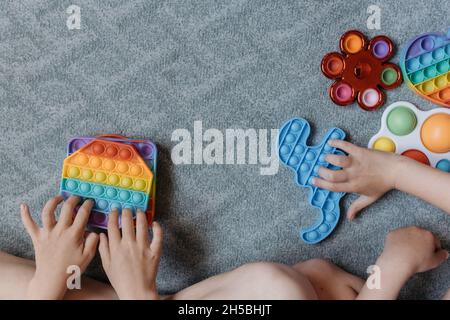 Vue d'en haut jusqu'aux enfants jouant avec des jouets pop IT.Bonne enfance Banque D'Images