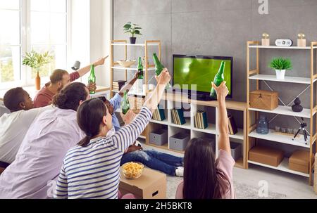 Groupe d'amis hommes et femmes assis devant la télévision en regardant émotionnellement le match de football. Banque D'Images