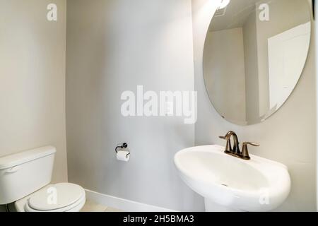 Petite salle de bains avec toilettes et lavabo sur pied avec miroir ovale Banque D'Images