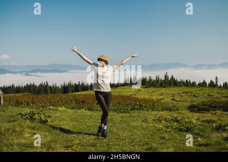 Voyageur au sommet de la montagne en profitant de la vue aérienne les mains soulevées au-dessus des nuages lors d'une chaude journée d'été.Magnifique paysage des Carpates bannière panorama Banque D'Images