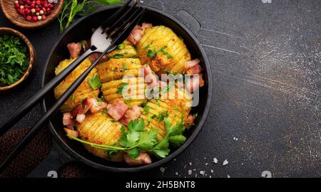 Pommes de terre cuites au four avec du jambon, des herbes et de la chapelure sur fond sombre.Cuisine scandinave.Vue de dessus. Banque D'Images