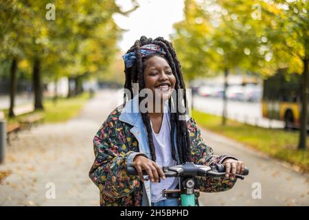 Une femme heureuse souriant en utilisant un scooter électrique Banque D'Images