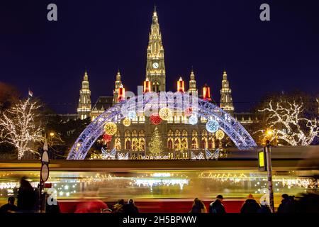 Le tram est en face du marché de Noël par l'hôtel de ville - Rathaus dans la nuit Vienne, Autriche. Banque D'Images