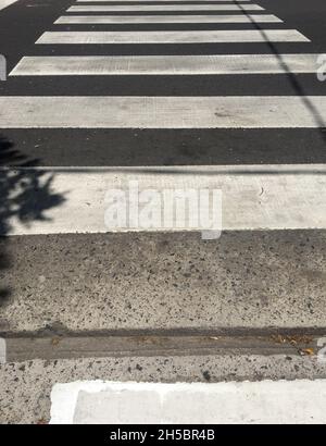 Bandes de zèbre blanches pour passage de trottoir sur la surface de la route asphaltée noire Banque D'Images