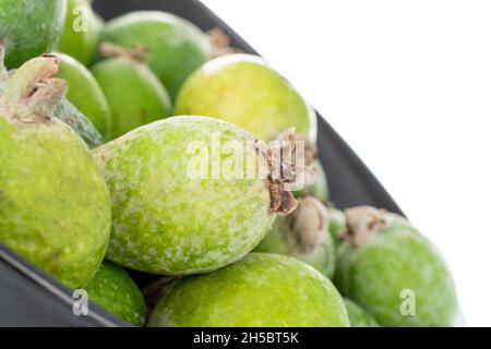 Plusieurs fruits féijoa doux mûrs avec une plaque en céramique, gros plan, isolés sur du blanc. Banque D'Images