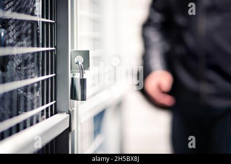 Cambrioleur ou voleur et stockage avec verrou dans le sous-sol du bâtiment d'appartement.Homme suspect, intrus et criminel.Porte avec cadenas pour plus de sécurité. Banque D'Images