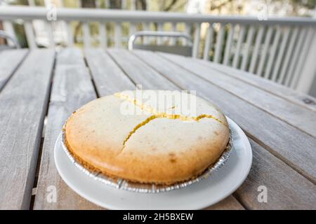 Gâteau au fromage plat entier maison cheesecake sur plaque à l'extérieur de la table en bois fond avec fissures craquelées échec de cuisson en raison de la température Banque D'Images