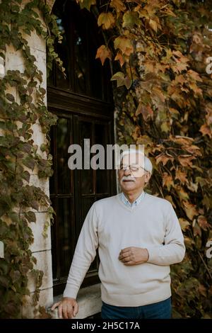 Homme âgé en bonne santé debout près de la fenêtre le jour de l'automne Banque D'Images