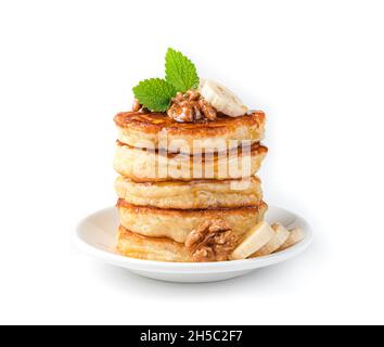 Une pile de crêpes aux noix, à la banane, à la menthe et au miel dans une assiette blanche isolée sur blanc.Vue latérale. Banque D'Images