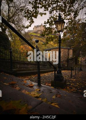 Château d'Édimbourg depuis les marches descendant jusqu'à la cour de l'église paroissiale de St Cuthbert, Kirk à côté des jardins de Princes Street.Heure d'automne. Banque D'Images