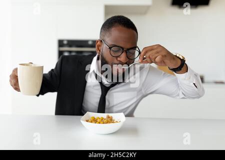 Homme noir se précipitant pour travailler manger des céréales à la maison Banque D'Images