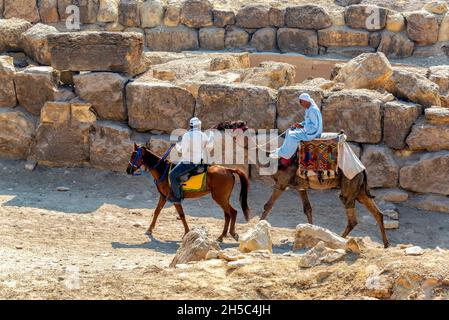 GIZA, EGYPTE - 14 JUILLET 2021 : un homme à dos de chameau et un homme à cheval près de la Grande Pyramide de Giza, Egypte Banque D'Images