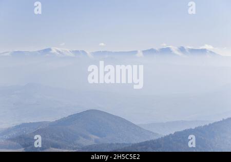 Vue sur les sommets de la crête de Borzhava couverts de nuages blancs et de forêt sous un ciel bleu clair le jour d'automne chaud d'octobre.Région de Lviv, Ukraine Banque D'Images