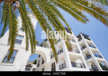 Maison avec appartements contre le ciel bleu et palmiers en Europe. Banque D'Images