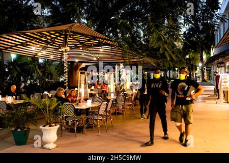 Miami Beach, États-Unis - 20 janvier 2021 : célèbre rue commerçante de Lincoln Road avec des gens qui marchent sur le trottoir près du café restaurant la nuit dans des masques covid-19 Banque D'Images