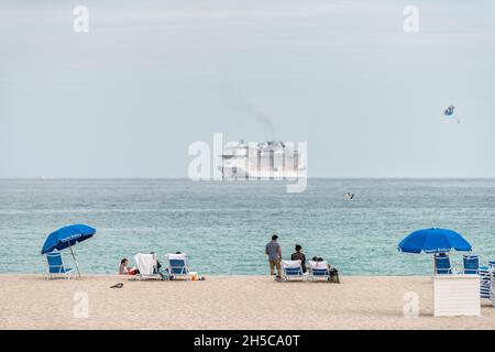 Miami, États-Unis - 17 janvier 2021 : côte de South Beach dans la ville de Floride, par beau temps, avec des gens sur le sable et les parasols avec de l'eau bleue colorée et des bancs de croisière Banque D'Images