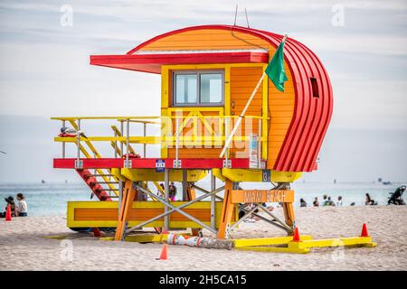 Miami Beach, États-Unis - 17 janvier 2021 : station de construction de huttes de sauveteurs orange colorées avec des gens à South Beach par l'océan Atlantique le jour nuageux Banque D'Images