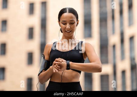 Jeune femme sportive regardant Smartwatch, suivi de l'activité physique pendant l'entraînement en plein air Banque D'Images