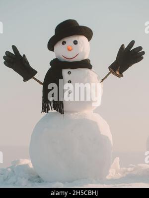 Bonhomme de neige avec chapeau et écharpe en hiver en plein air.Bonhomme de neige en hiver chapeau, écharpe et gants noirs.Noël et hiver. Banque D'Images