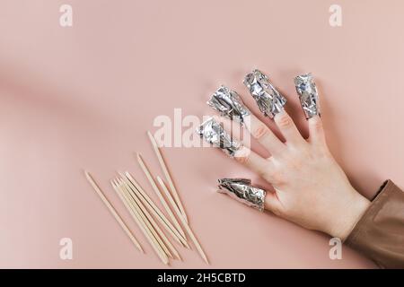 Le processus d'élimination du vernis à gel des ongles.Les ongles sont enveloppés dans de la Falga sur un fond rose.Copier l'espace. Banque D'Images