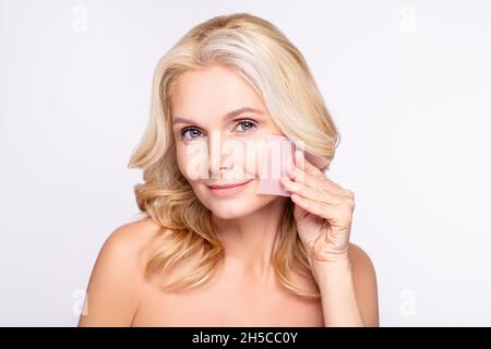 Photo d'une femme d'âge attrayante sourire positif heureux massant serviette de peau isolée sur fond gris Banque D'Images