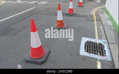 Vue sur la rue anglaise avec des cônes de signalisation, des marques jaunes et blanches Banque D'Images