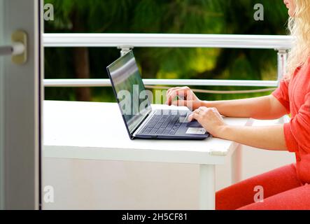 Femme travaillant sur son ordinateur portable sur le balcon Banque D'Images