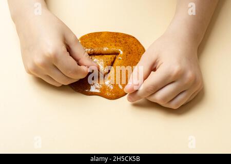 Biscuit de sucre en nid d'abeille de Dalgona coréen avec des formes de triangle. Mains jouer nouveau défi de bonbons tendance Banque D'Images