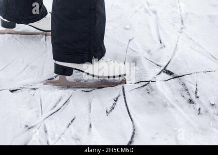 Photo en gros plan des patins.Patins de patinage à figurine blanche, la personne apprend aux monter sur la glace d'un lac gelé en hiver Banque D'Images