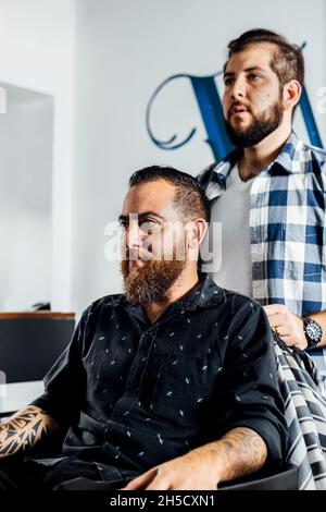 Client d'un salon de coiffure qui attend un manteau de coiffure. Banque D'Images