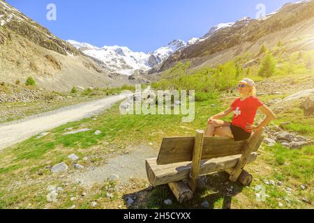 Femme avec t-shirt drapeau suisse sur le sentier de randonnée au glacier de Morteratsch en Suisse.Plus grand glacier de la chaîne de Bernina des Alpes de Bundner Banque D'Images