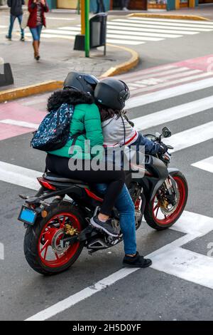 Deux femmes en moto attendent au feu de circulation dans une rue de la ville pendant la journée Banque D'Images