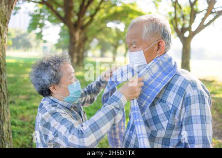 Un couple senior s'aide à porter un tissu d'hiver chaud Banque D'Images