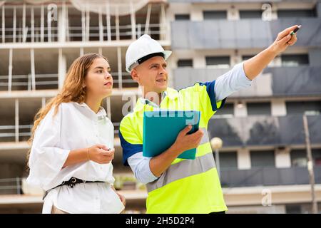 Le constructeur discute avec le client sur le chantier de construction Banque D'Images