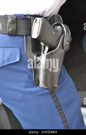 Gros plan vertical d'un pistolet dans une poche en cuir collée sur la ceinture d'un policier. Banque D'Images