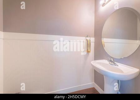 Lavabo sur pied avec serviette suspendue sur le côté et miroir ovale dans une petite salle de bains Banque D'Images